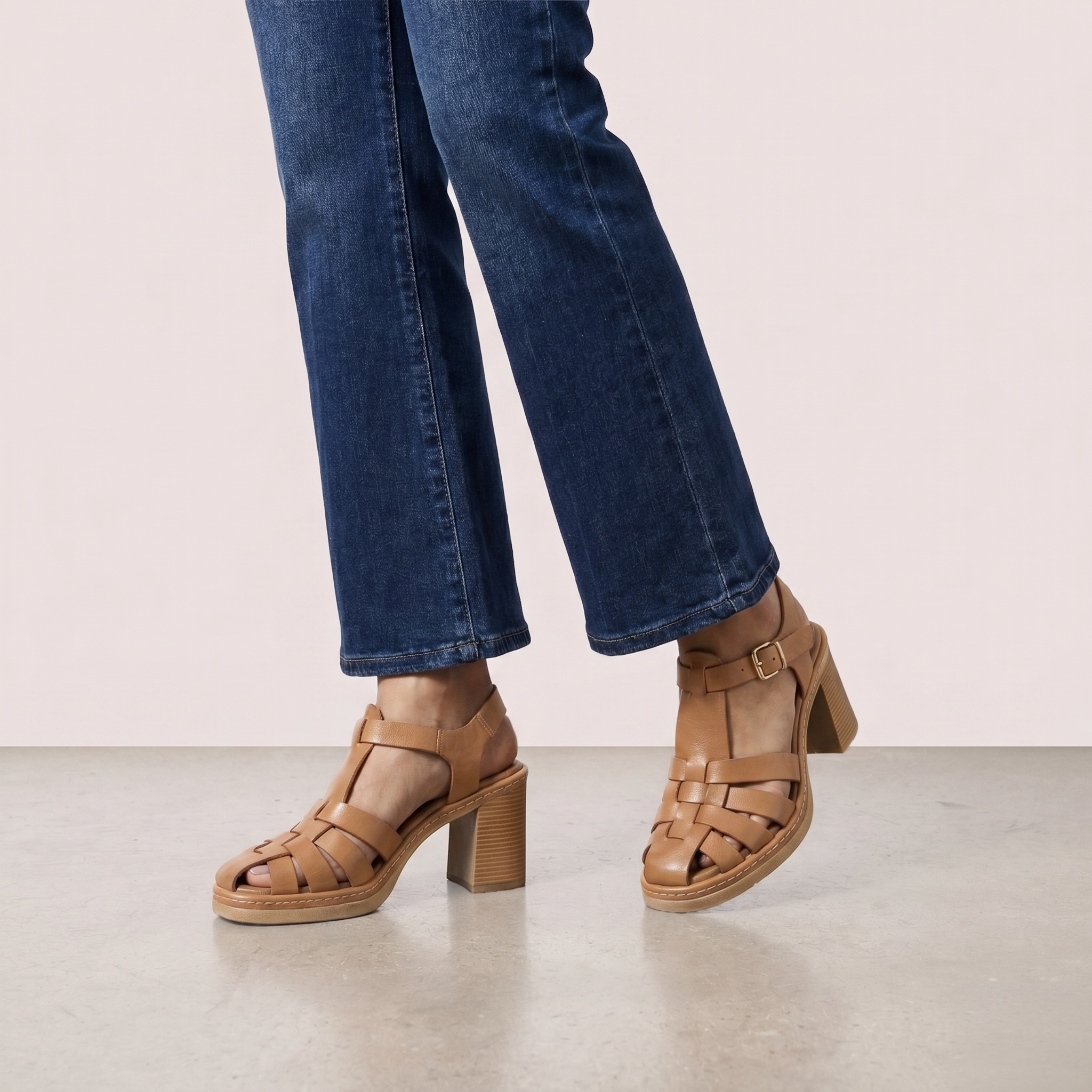 Brown woven sandals worn with blue jeans on a light background
